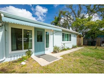 Inviting home front entrance with awning, blue door and trim, surrounded by lush landscaping and a clear walkway at 221 Nippino E Trl, Nokomis, FL 34275