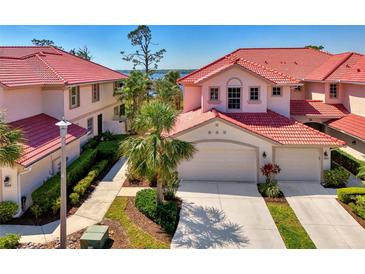 Beautiful building exterior with lush landscaping, barrel tile roof, and paver driveway leading to a two-car garage at 4692 Club Dr # 101, Port Charlotte, FL 33953