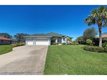Charming single-story home featuring a well-manicured lawn, three-car garage, and tropical landscaping at 1078 Boundary Blvd, Rotonda West, FL 33947