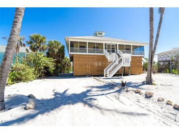 Stunning elevated beach house with white stairs and beautiful landscaping in a sunny, coastal setting at 342 S Gulf Blvd, Placida, FL 33946