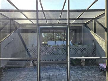 View of the screened lanai with brick pavers and view of the home's entrance at 351 Bobby Jones Rd # 351, Sarasota, FL 34232