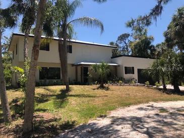 Two-story home featuring a landscaped yard, palm trees, and an attached two-car garage at 425 Laurel W Rd, Nokomis, FL 34275