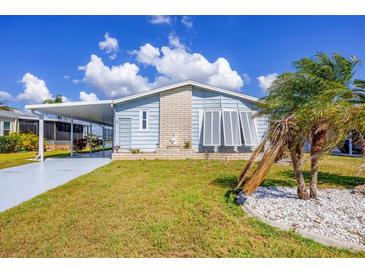 Charming single-story home with a covered carport, well-maintained lawn, and beautiful palm trees at 809 Tangerine Woods Blvd # 215, Englewood, FL 34223