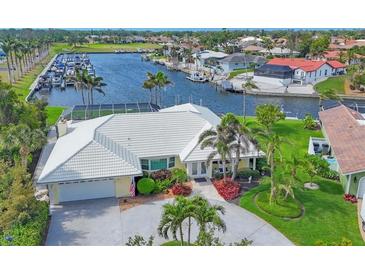 Waterfront home with white tile roof, lush landscaping, and private dock, near the marina and boat slips at 44 Waterford Dr, Englewood, FL 34223