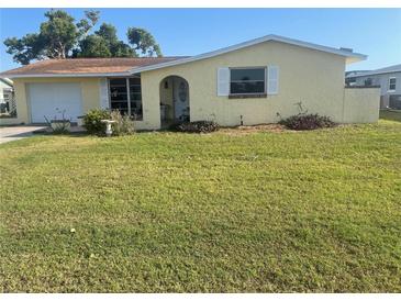 Charming one-story yellow home with a garage and well-maintained front yard at 81 Oakland Hills Pl, Rotonda West, FL 33947