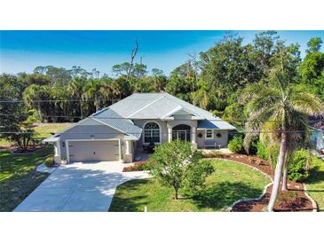 Charming home featuring a meticulously manicured lawn, lush tropical landscaping, and a welcoming two-car garage at 941 Elwood Ave, Englewood, FL 34223