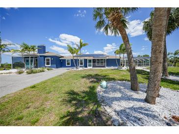 Charming blue single-story home with tropical landscaping, and a sunny driveway at 24805 Nova Ln, Punta Gorda, FL 33980