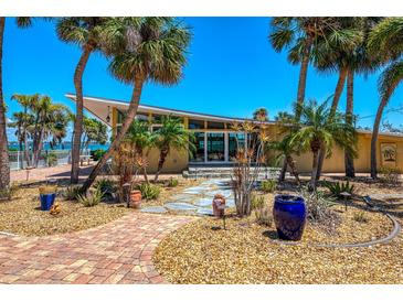 Inviting front exterior with lush landscaping, palm trees, and a unique mid-century modern roofline at 6029 Manasota Key Rd, Englewood, FL 34223