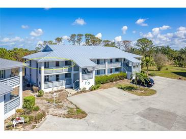Condominium exterior featuring a gray metal roof and a private balcony with seating and manicured landscaping at 6800 Placida Rd # 262, Englewood, FL 34224