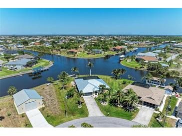 Gorgeous aerial view of a waterfront home featuring a canal, lush landscaping, and a private boat dock at 9404 Arnaz Cir, Port Charlotte, FL 33981