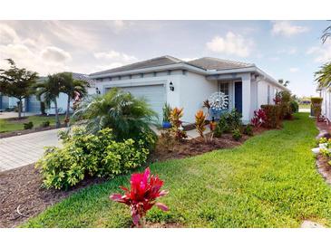 Beautifully landscaped front yard with colorful plants and well-maintained lawn at 9853 Bright Water Dr, Englewood, FL 34223