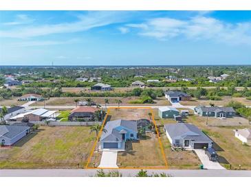 Aerial view of a bright blue one-story home with a grey roof, screened in patio and an attached two-car garage at 12359 Deepwoods Ave, Port Charlotte, FL 33981