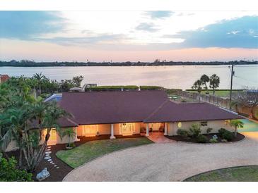 Waterfront home featuring a beautiful backyard, well manicured landscaping and a circular driveway at 1275 Bayshore Dr, Englewood, FL 34223