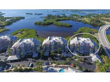Stunning aerial view of waterfront condos, showcasing lush landscaping, bay views, and a resort-style pool at 13113 Gasparilla Rd # A503, Placida, FL 33946