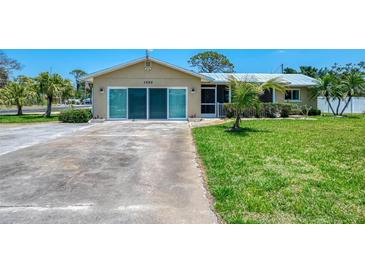 Charming single-story home featuring a well-manicured lawn, metal roof, and a welcoming screened-in porch at 1585 Poinciana Rd, Venice, FL 34293