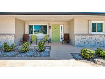 Inviting front porch with seating and a vibrant green door, framed by lush landscaping at 1915 Illinois Ave, Englewood, FL 34224