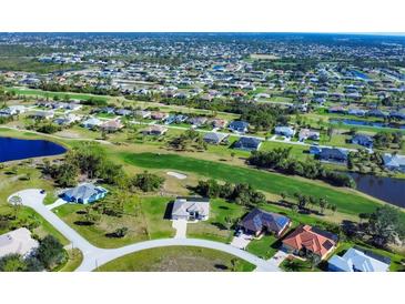 Expansive aerial view of a residential neighborhood with golf course and pond, highlighting community living and lush green spaces at 27 Tee View Rd, Rotonda West, FL 33947