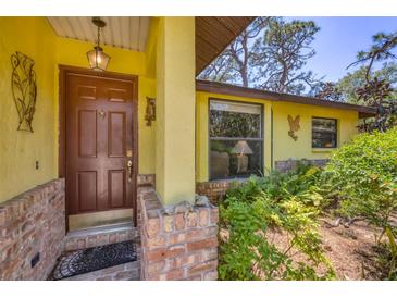 Charming front door with decorative brick accents and a welcoming entryway with lush landscaping at 521 Artists Ave, Englewood, FL 34223