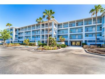 Modern condo building featuring multiple stories, balconies, and tropical landscaping on a sunny day at 8413 Placida Rd # 205, Placida, FL 33946
