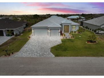 Beautiful single Gathering home featuring a three car garage, paver driveway, and well-manicured lawn at 10115 Long Branch St, Port Charlotte, FL 33981