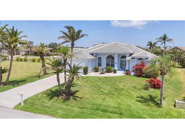 Beautiful one-story home with well-manicured lawn, lush landscaping, and a light blue exterior paint at 11 Amberjack Ln, Placida, FL 33946