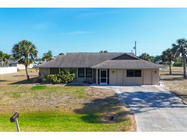 Charming single-story home with a well-maintained lawn, complemented by palm trees and a long driveway at 11869 Newgate Ave, Port Charlotte, FL 33981