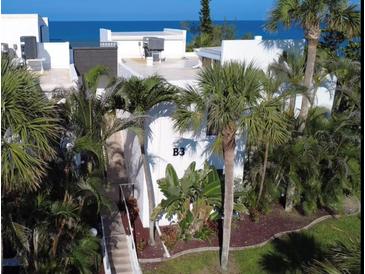 Tropical white condo building, B3 unit, surrounded by palms, fronted by walkway, with ocean view at 2950 N Beach Rd # B324, Englewood, FL 34223