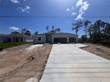 Newly built single-Gathering home with a three-car garage and freshly poured concrete driveway on a sunny day at 5273 Gillot Blvd, Port Charlotte, FL 33981