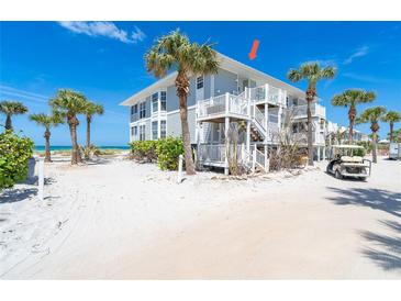 Coastal beach house with white railings and stairs plus tropical landscaping and a golf cart at 7548 Palm Island S Dr # 1724, Placida, FL 33946