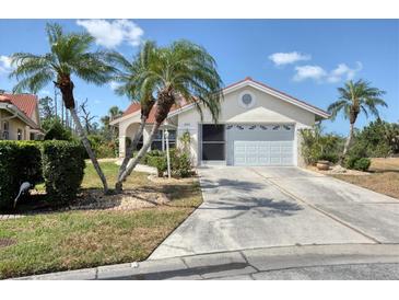 Charming single-story home with a two-car garage, tile roof, and beautiful landscaping including palm trees at 8320 Creekview Ln, Englewood, FL 34224