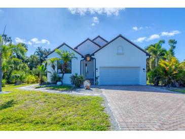 Charming single-Gathering home with a well-manicured lawn, brick driveway, and tropical landscaping at 161 Haddock Dr, Rotonda West, FL 33947