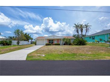Charming single-story home featuring lush landscaping, a manicured lawn, and a long driveway at 18451 Goodman Cir, Port Charlotte, FL 33948
