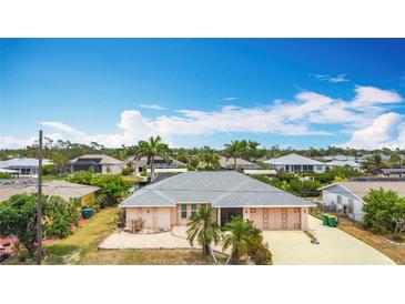 A single-story home boasts a well-manicured lawn, a two-car garage, and a charming, neutral-colored exterior at 18790 Countryman Ave, Port Charlotte, FL 33948