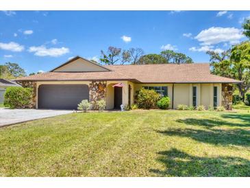 Charming single-story home featuring a well-manicured lawn, a stone-accented facade, and an attached two-car garage at 5879 Venisota Rd, Venice, FL 34293