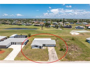 Aerial view of charming single-story home on a golf course with a long driveway and mature landscaping at 11 Oakland Hills Rd, Rotonda West, FL 33947