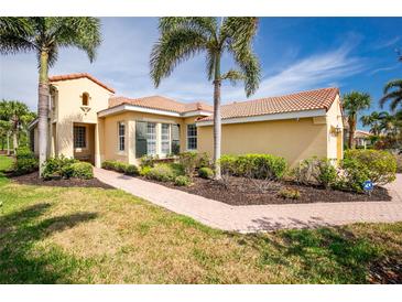 Inviting single-story home with lush landscaping, a brick walkway, and a beautiful terra cotta tile roof at 142 Savona Way, North Venice, FL 34275
