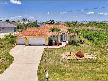 Beautiful waterfront home featuring mature landscaping, an arched entry, and a three-car garage at 15020 Acorn Cir, Port Charlotte, FL 33981