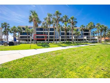 Three-story condo building with palm trees, balconies, and manicured lawn in a sunny, tropical setting at 1551 Beach Rd # 212, Englewood, FL 34223