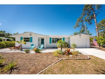 Inviting home features a well-manicured front yard with vibrant landscaping and a freshly painted exterior at 1691 Lakeview Pl, Englewood, FL 34223