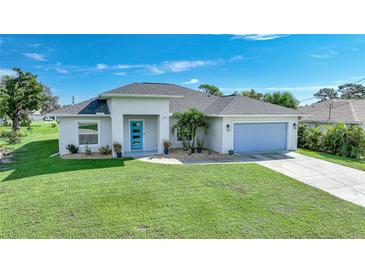 Inviting single-story home with a well-manicured lawn, featuring a modern blue front door and coordinated garage door at 171 Mark Twain Ln, Rotonda West, FL 33947