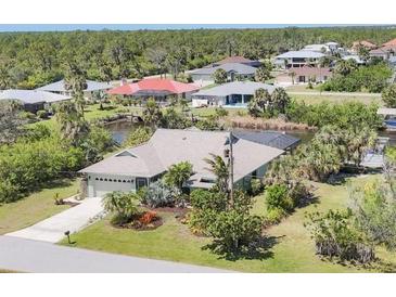 Charming home with lush landscaping, a canal view, and an attached two-car garage at 2441 Vance Ter, Port Charlotte, FL 33981