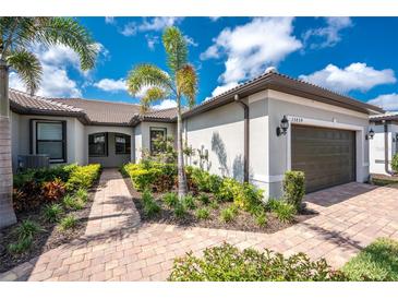 Charming single-story home featuring a landscaped front yard, brick pathway, and tropical palm trees against a blue sky at 13859 Vadini St, Venice, FL 34293