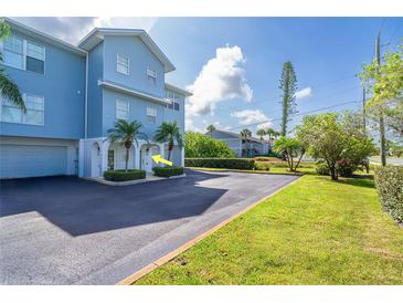 Coastal condo building with blue siding, tropical landscaping, and private garage entrances at 3929 Cape Haze Dr # 101, Rotonda West, FL 33947