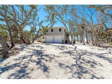 Beautiful two-story home featuring a two-car garage, neutral paint, and lots of trees at 6430 Manasota Key Rd, Englewood, FL 34223