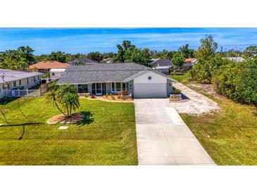 Charming one-story home featuring a long driveway, a well-manicured lawn and a tropical tree at 9869 Gulfstream Blvd, Englewood, FL 34224