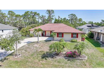 Charming single-story home with well-maintained landscaping, circular driveway, and a red tile roof at 13080 Proctor Ave, Port Charlotte, FL 33981