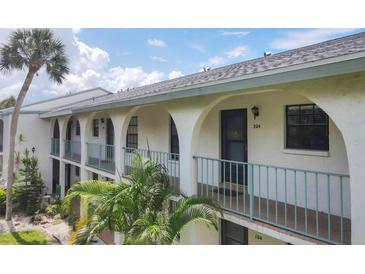Condo's exterior features archways, a balcony, and lush tropical landscaping at 1730 Manasota Beach Rd # 204, Englewood, FL 34223