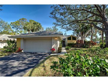 Charming single-Gathering home featuring a manicured lawn, mature trees, and a two-car garage on a sunny day at 232 Southampton Ln # 259, Venice, FL 34293