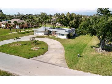 Charming single-story home boasts a circular driveway, lush lawn, and a roof equipped with modern solar panels at 310 Green Dolphin Dr, Placida, FL 33946