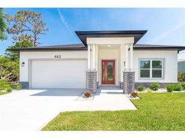 Charming single-story home with a well-manicured lawn, red front door, and two-car garage at 482 Sunset N Rd, Rotonda West, FL 33947